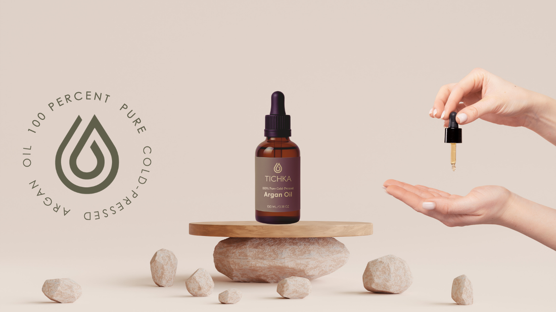 Cosmetic Argan Oil Bottle on stand and hand holding oil dropper