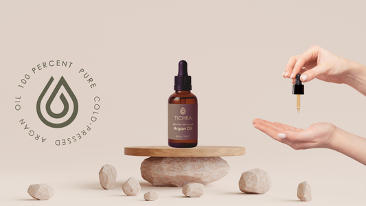 Cosmetic Argan Oil Bottle on stand and hand holding oil dropper