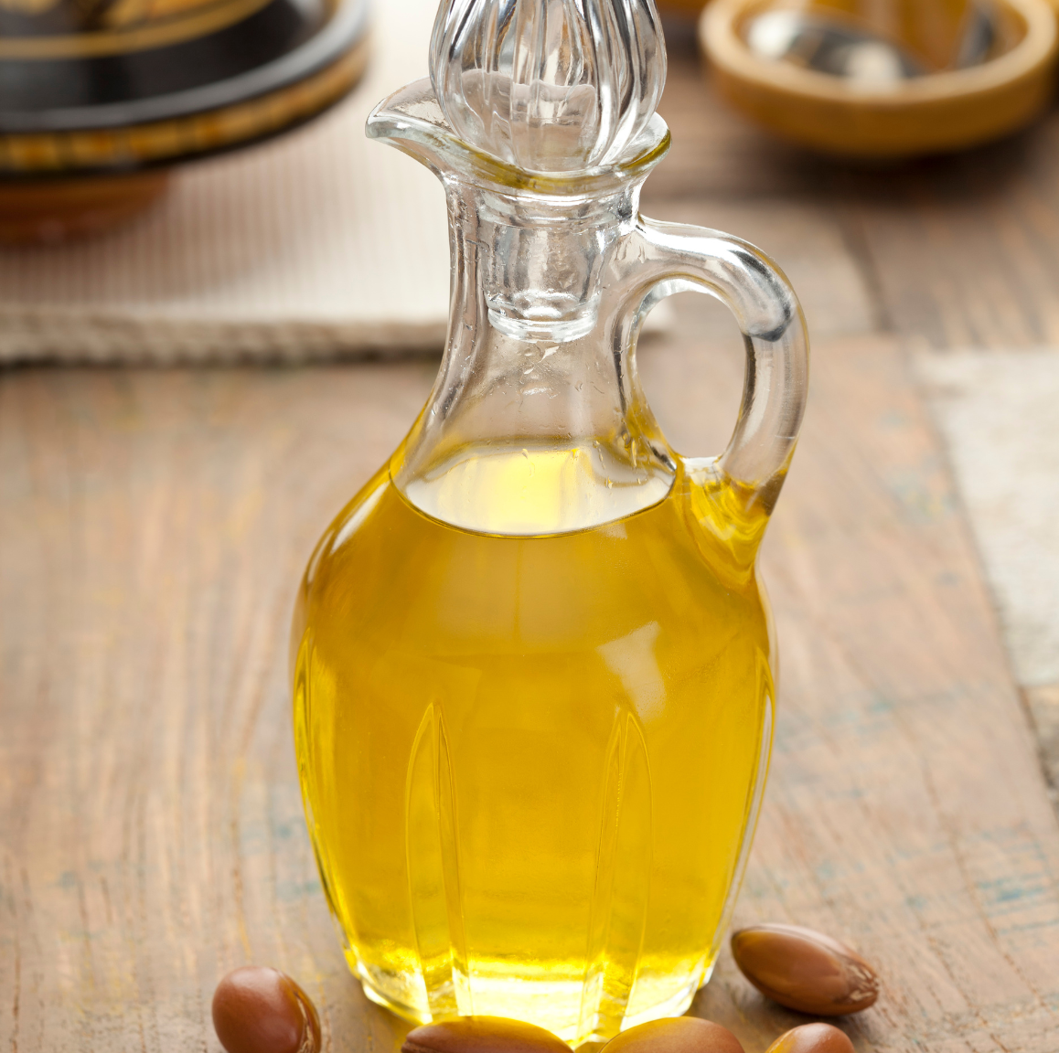 Glass bottle of oil with argan seeds on a wooden surface