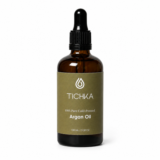A 100 mL amber glass dropper bottle of Tichka Argan Oil with a black dropper cap and an olive green label, shown on a white background.